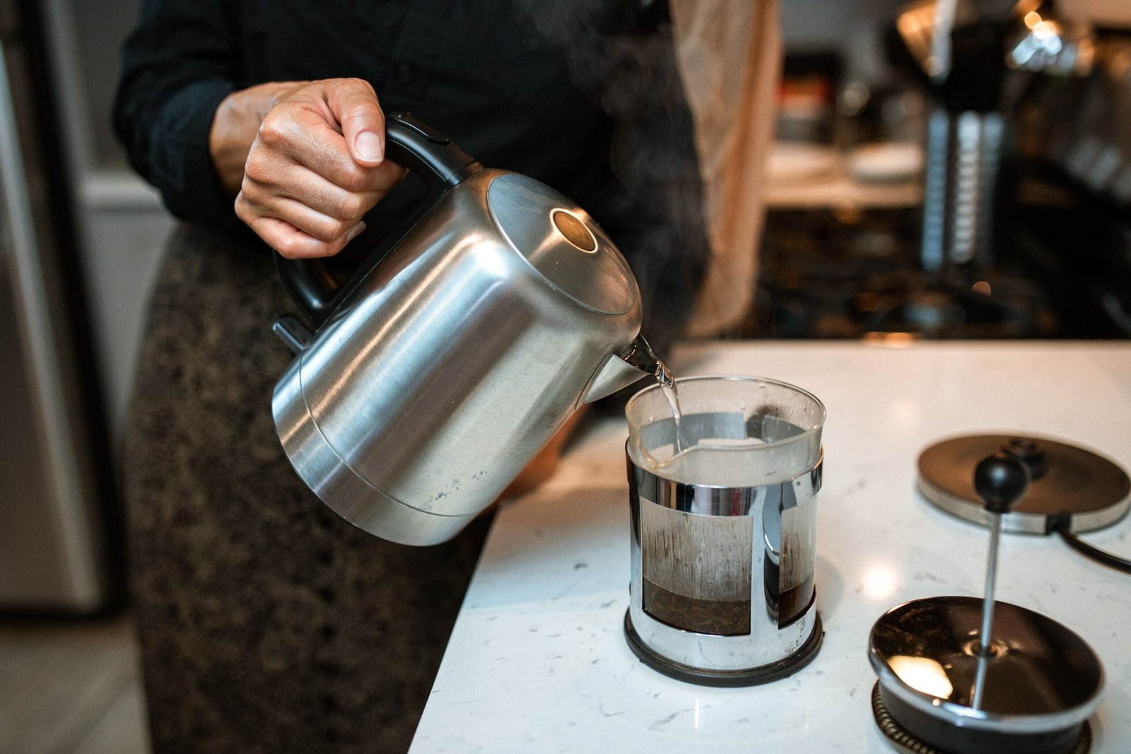 Pouring hot water into a coffee press in a home kitchen